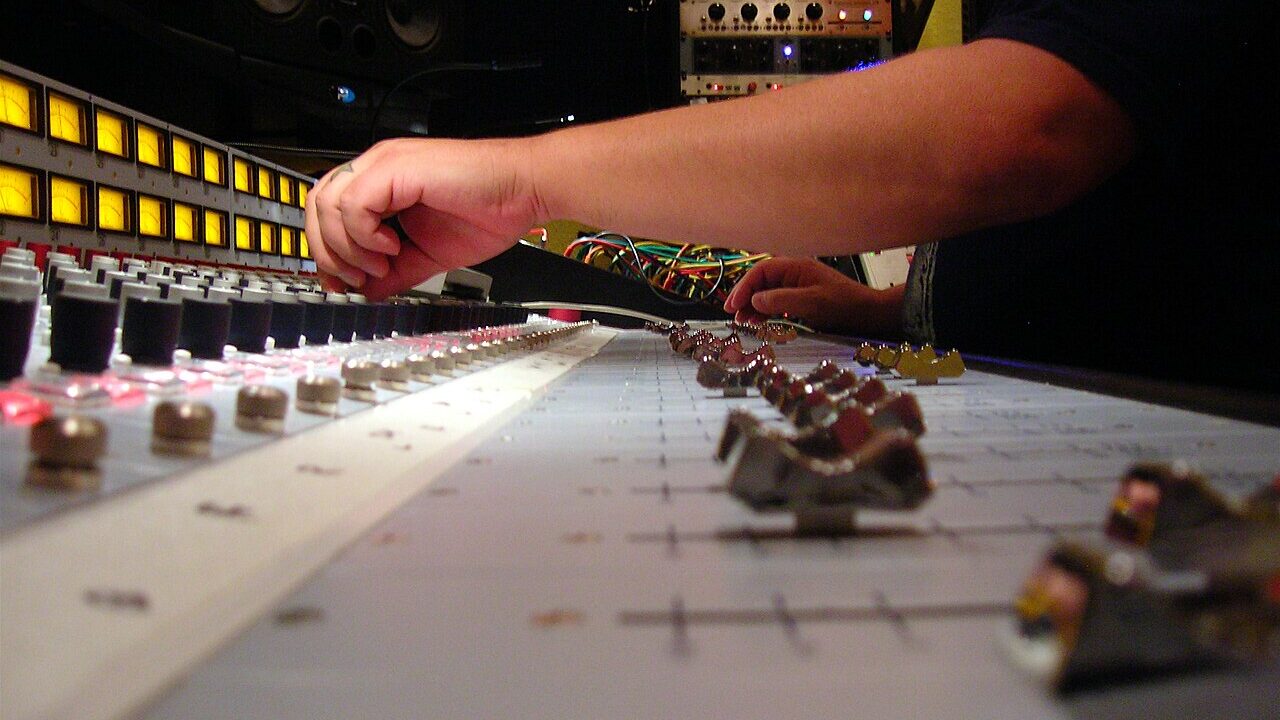 Hands adjusting a recording mixing console