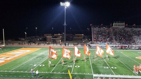 High school football field at night under floodlights