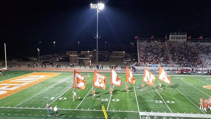 High school football field at night under floodlights