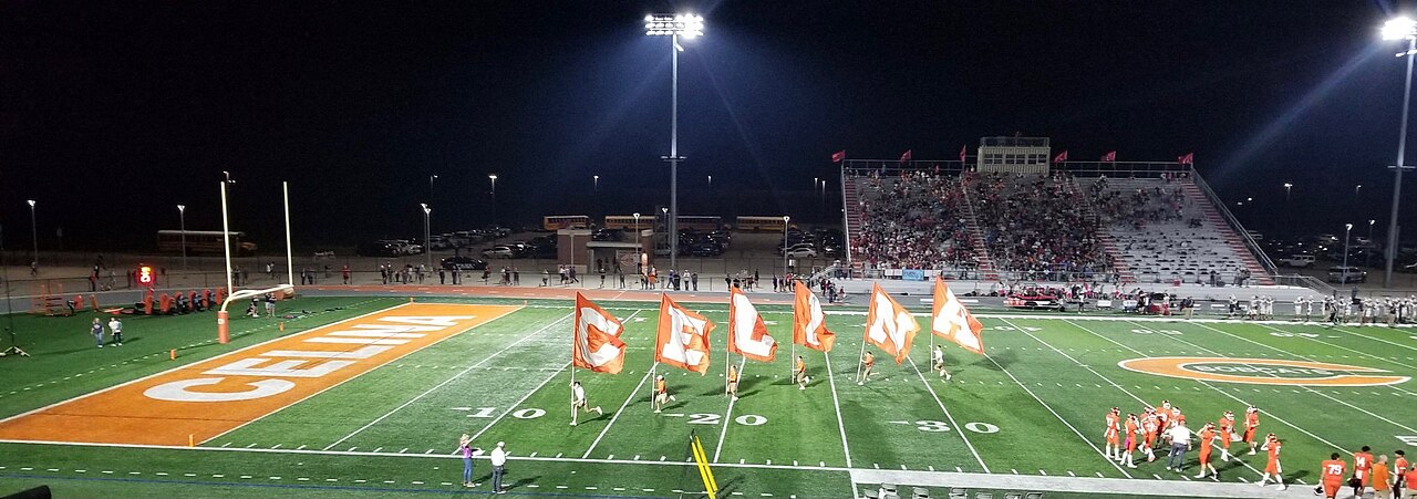 High school football field at night under floodlights
