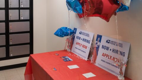 USPS Now Hiring signs at a post office